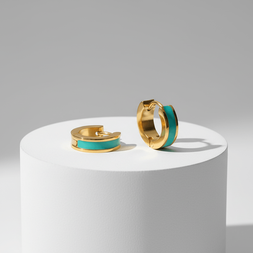 Gold Enamel Huggie Hoop Earrings with turquoise enamel on a white platform against a gray background