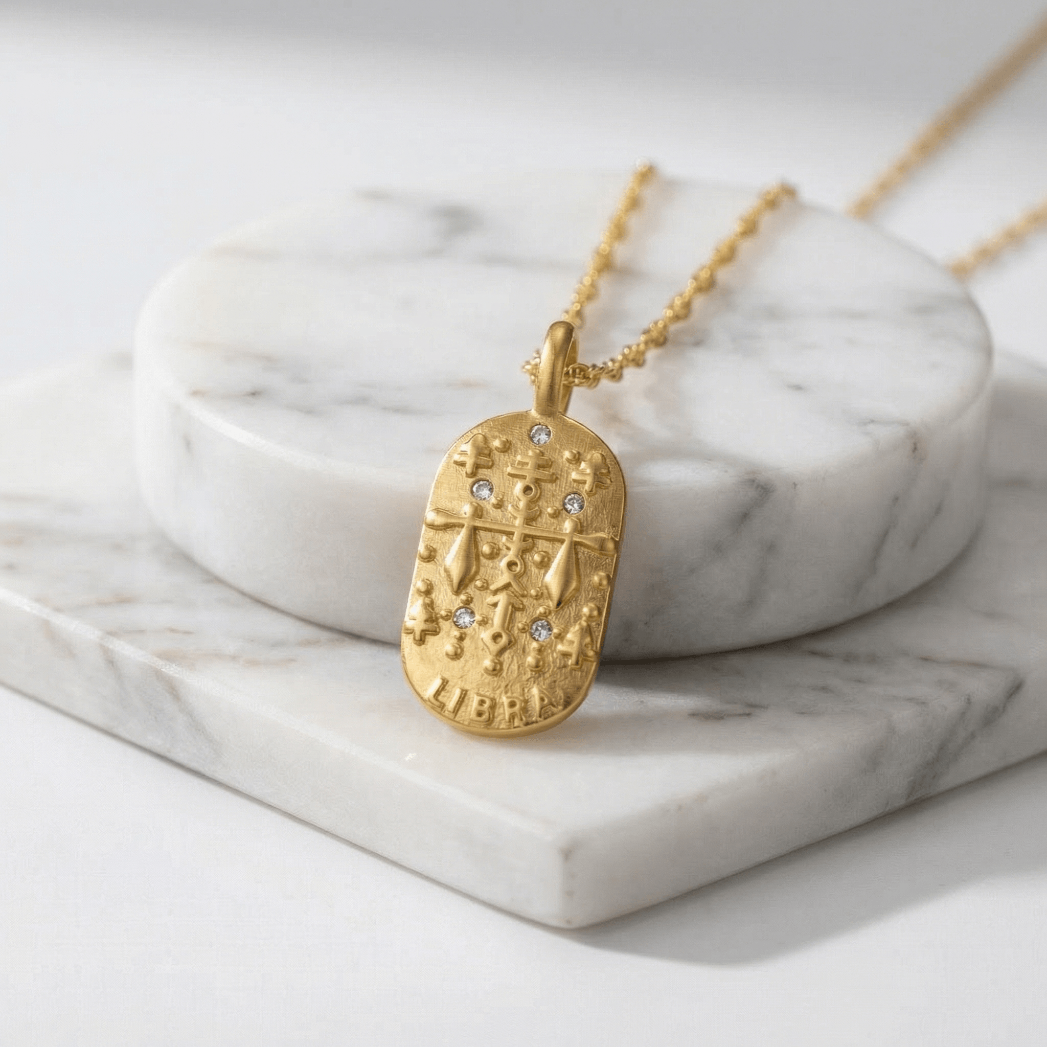 Libra Gold Engraved Zodiac Sign Necklace on a marble surface