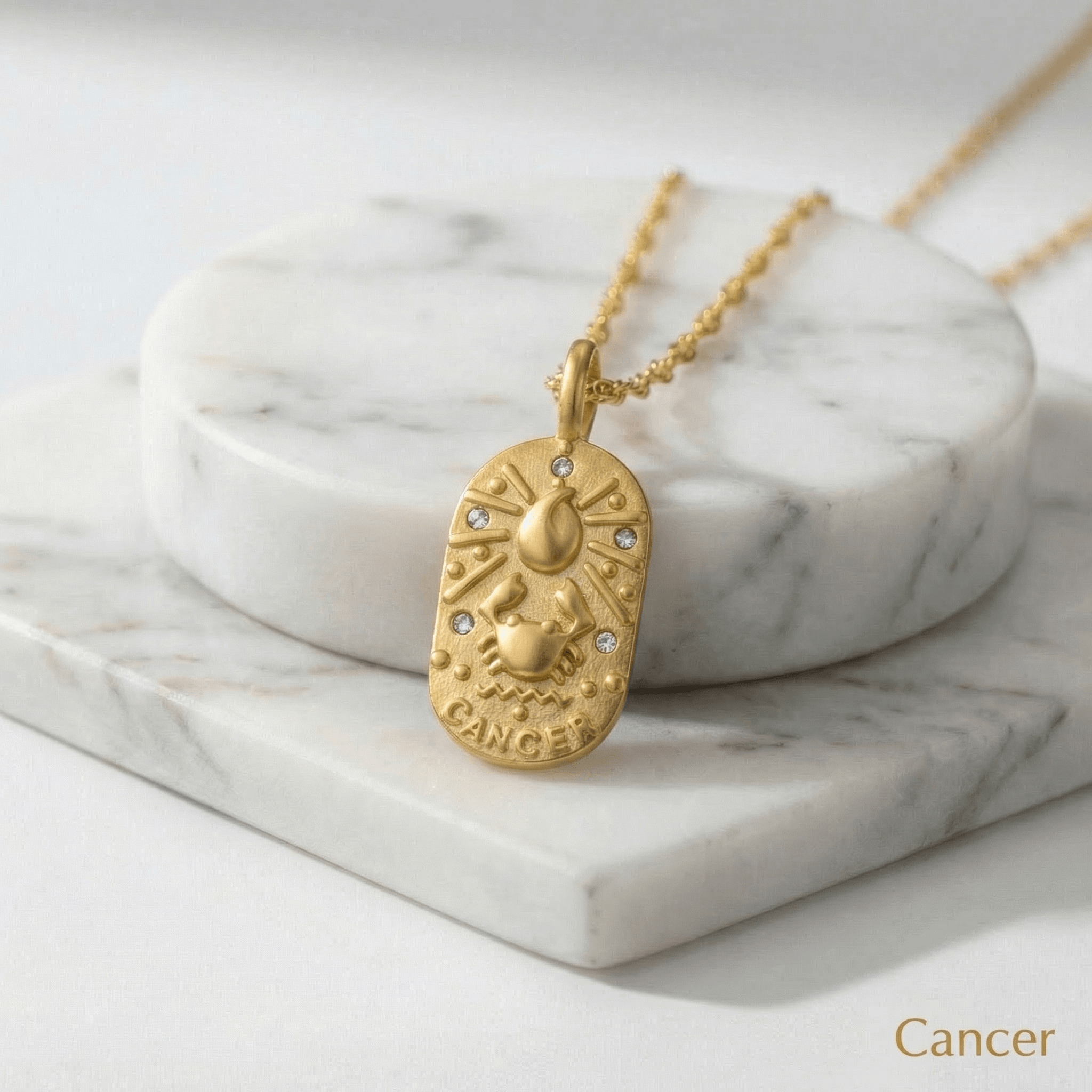 Cancer Gold Engraved Zodiac Sign Necklace on a marble surface