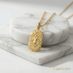 Capricorn Gold Engraved Zodiac Sign Necklace on a marble surface
