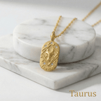 Taurus Gold Engraved Zodiac Sign Necklace on a marble surface