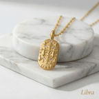 Libra Gold Engraved Zodiac Sign Necklace on a marble surface with 'Libra' text