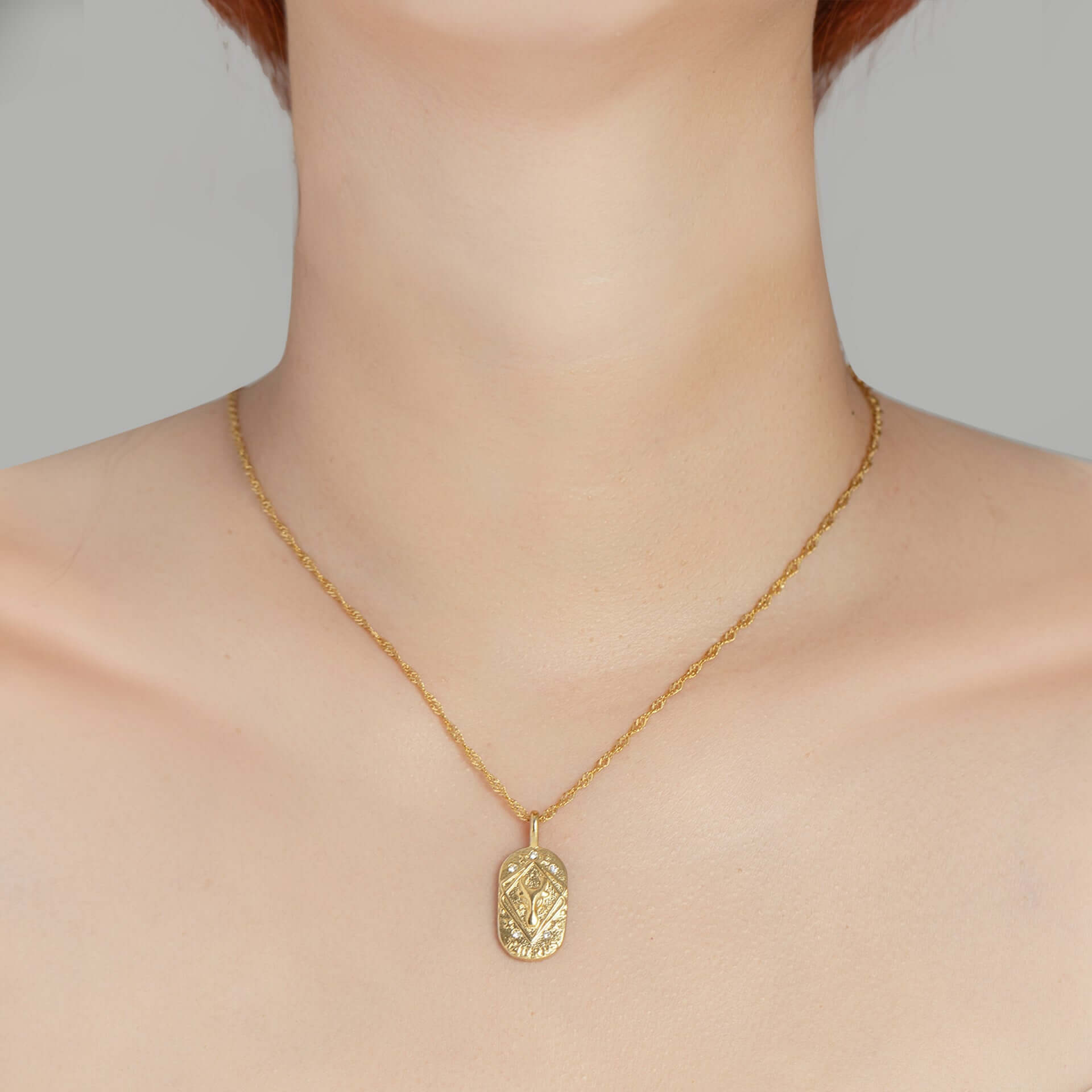 Gold Engraved Zodiac Sign Necklace displayed on a model's neck, showcasing its detailed zodiac symbol and gold finish.