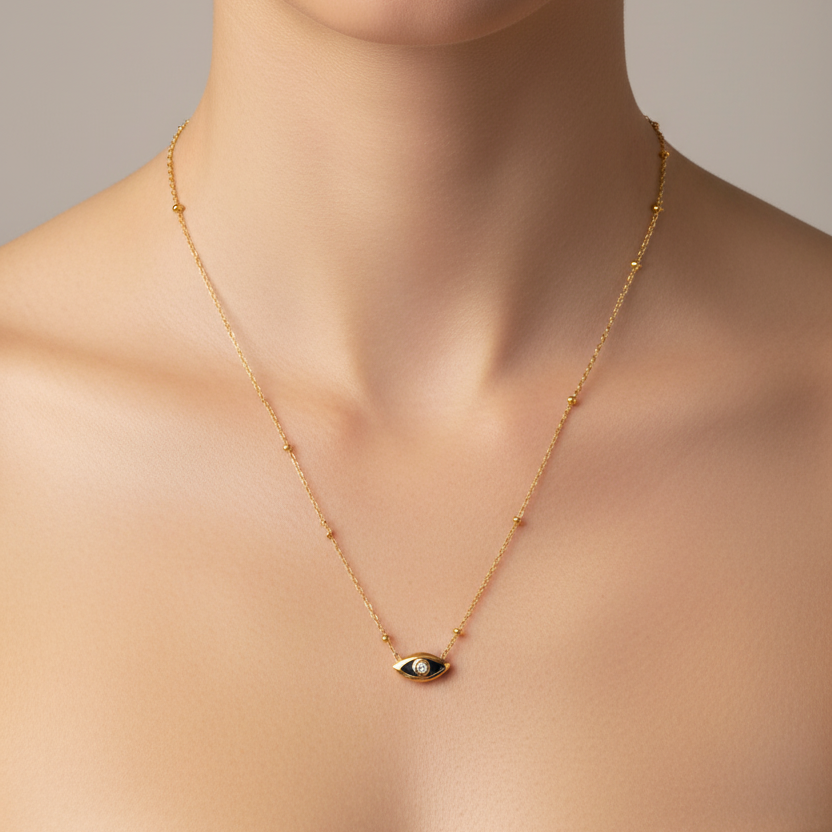 A delicate Gold Evil Eye Mini Charm Necklace,  shown worn on a model's neck against a soft gray background.
