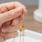 Gold Flower Pendant Necklace held by a hand against a neutral background