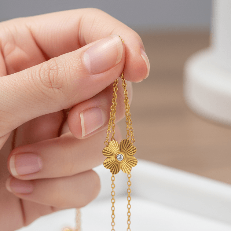 Gold Flower Pendant Necklace held by a hand against a neutral background