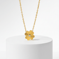 Gold Flower Pendant Necklace with a flower-shaped pendant on a white pedestal against a light gray background