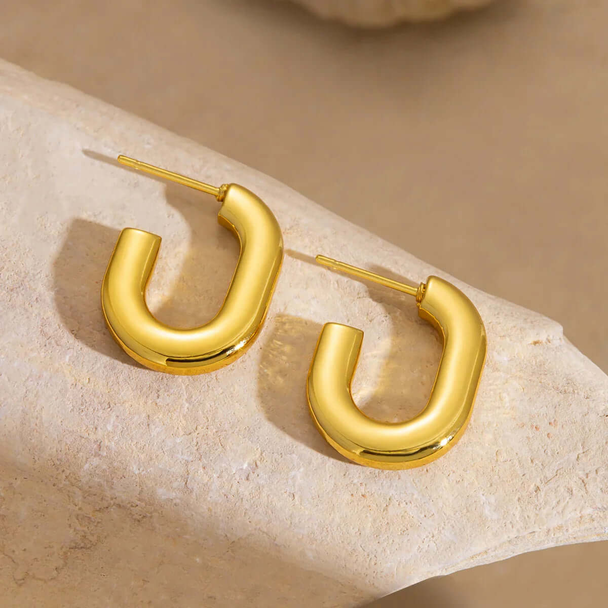 Ceyrah Gold Half Hoop Earrings with modern U-shape design on stone background