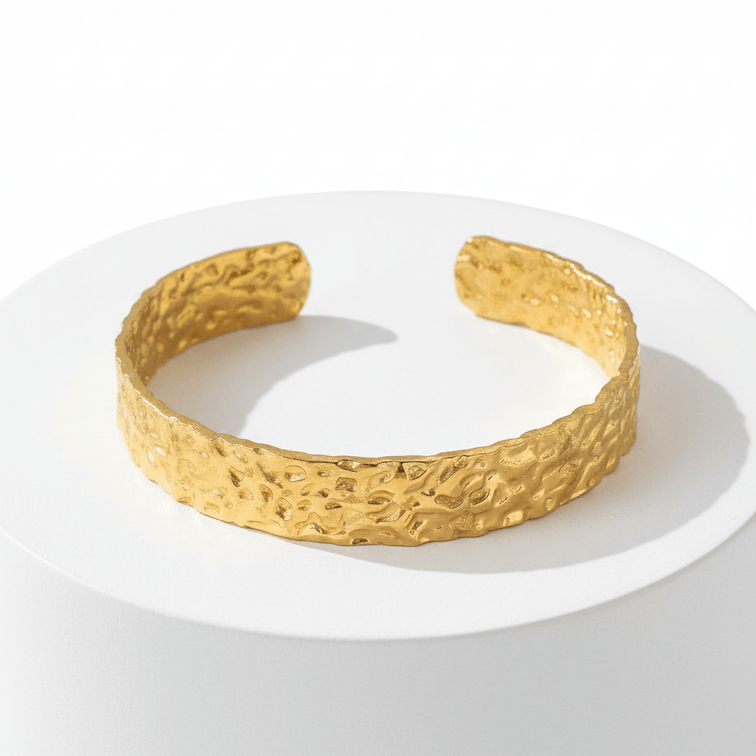 Gold Hammered Cuff Bracelet on a white pedestal with a white background