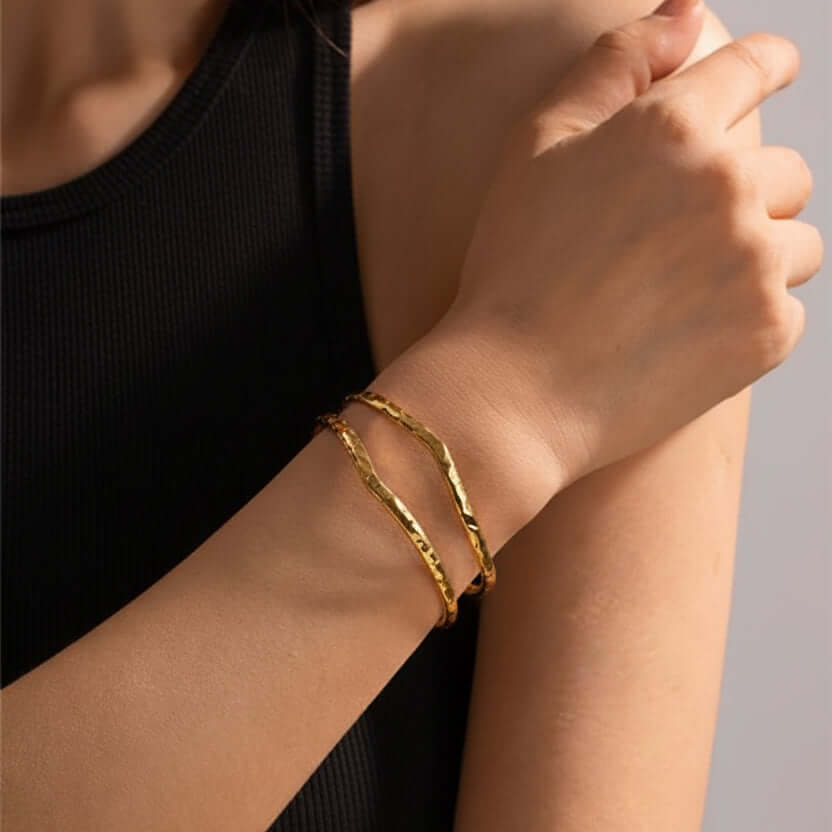 Person wearing a Gold Hammered Wave Cuff Bracelet on a neutral background