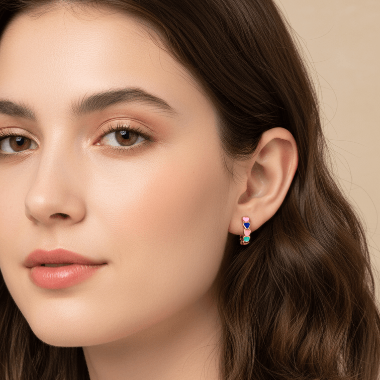 Close-up of a woman wearing Gold Heart Charm Hoop Earrings with a neutral background