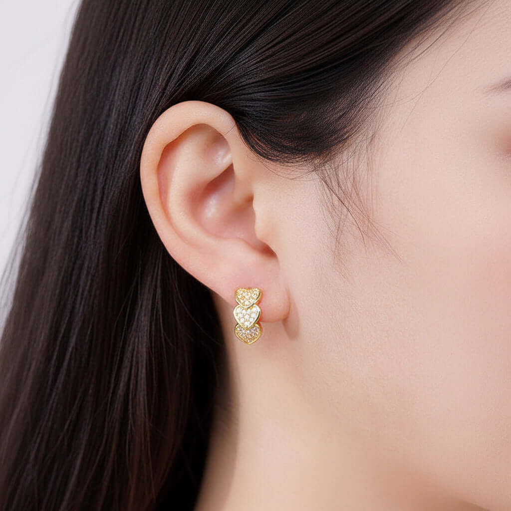 Gold heart-shaped earring worn by a person