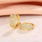 Gold Heart Crystal Cluster Hoop Earrings with clear stones on a light pink background