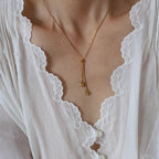 A close-up of a model wearing a delicate Gold Heart Drop Y Necklace Adjustable with two small dangling heart charms, styled with a white lace-trimmed blouse.