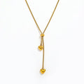 A Gold Heart Drop Y Necklace Adjustable featuring a textured chain, a central bead, and two dangling heart charms, shown on a plain white background.