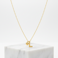 A delicate Gold Heart & I Initial Pendant Necklace, displayed on a white marble block against a clean white background.