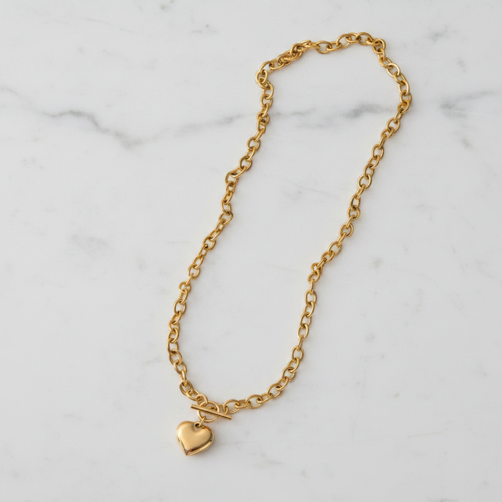 A Gold Heart OT Toggle Necklace, displayed on a white marble surface.