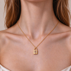 A close-up of a model's neck and chest wearing a Gold Heart Padlock Necklace with a small padlock pendant featuring a heart-shaped crystal inlay.