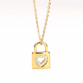Gold Heart Padlock Necklace featuring a padlock pendant with a heart-shaped cutout adorned with small clear stones, suspended from a delicate gold chain against a plain white background.
