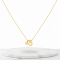 Gold Heart & S Initial Pendant Necklace displayed on a white marble pedestal against a white background.