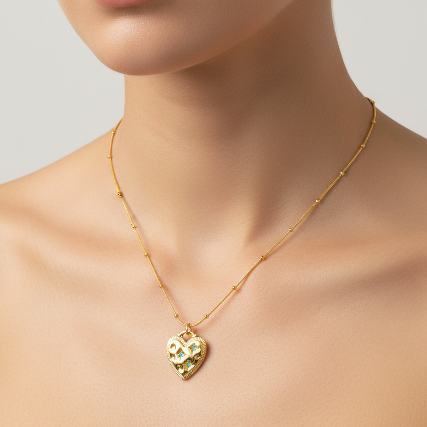 A close-up of a model's neck and chest wearing a delicate Gold Heart Turquoise Gemstone Necklace featuring green and gold inlay.