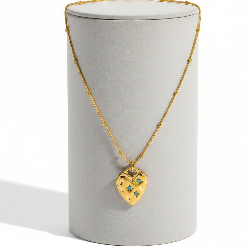 A Gold Heart Turquoise Gemstone Necklace pendant displayed on a light gray cylindrical stand against a white background.