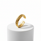 Gold Interlocking Leaf Ring displayed on a white pedestal showcasing its intricate interlocking leaf design.