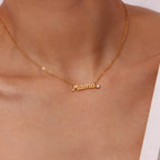 Gold Mama Necklace With Rhinestone Detail worn on a model's neck, featuring a cursive 'Mama' nameplate pendant with a small clear stone accent.