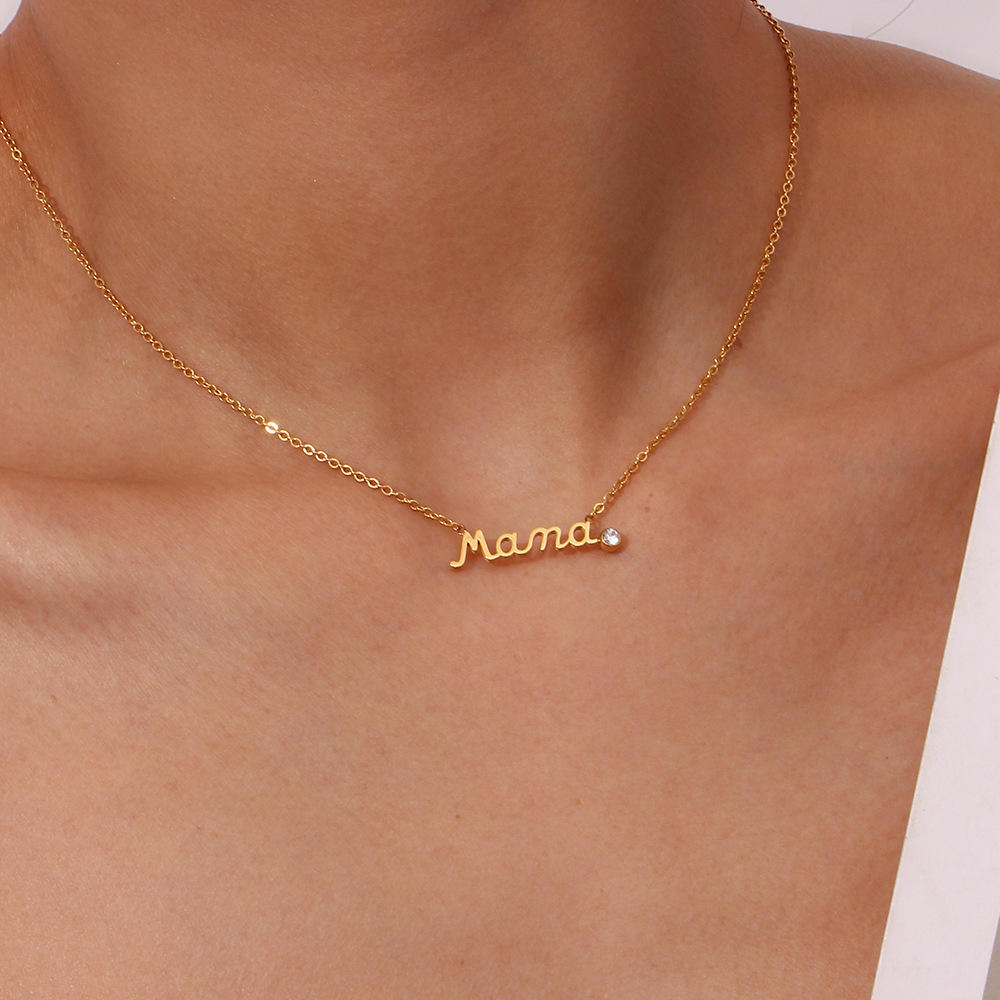 Gold Mama Necklace With Rhinestone Detail worn on a model's neck, featuring a cursive 'Mama' nameplate pendant with a small clear stone accent.