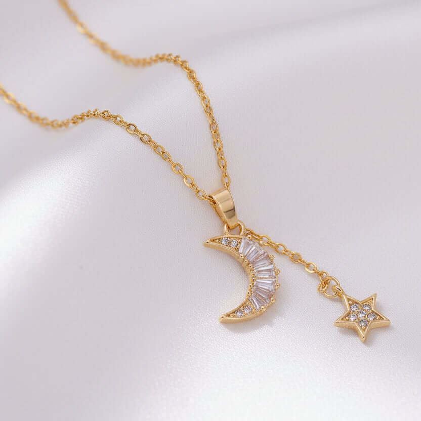Gold Moon & Star Celestial Necklace with moon and star pendants on a soft pink background