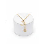 Gold Moon & Star Celestial Necklace with moon and star pendant on a white stand