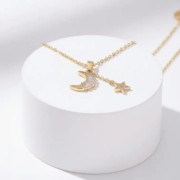 Gold Moon & Star Celestial Necklace with moon and star charms on a white stand against a light gray background