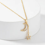 Gold Moon & Star Celestial Necklace with moon and star pendants on a white stand