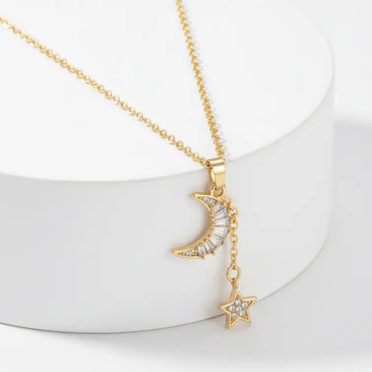 Gold Moon & Star Celestial Necklace with moon and star pendants on a white stand