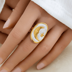 Gold Moon and Star Oval Ring displayed on a hand with a polished gold-tone frame and smooth white center.