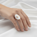 Hand wearing a Gold Oval Statement Ring on a white fabric background