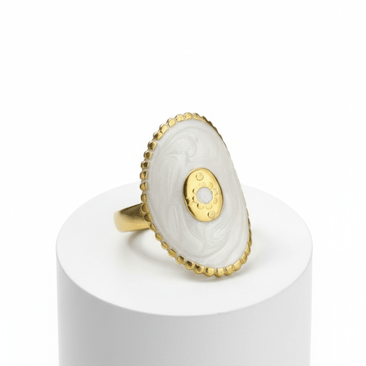 Gold Oval Statement Ring with a stone on a white cylindrical stand against a white background