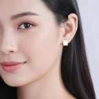 Gold Rectangular Huggie Hoop Earrings worn by a person with dark hair on a light background