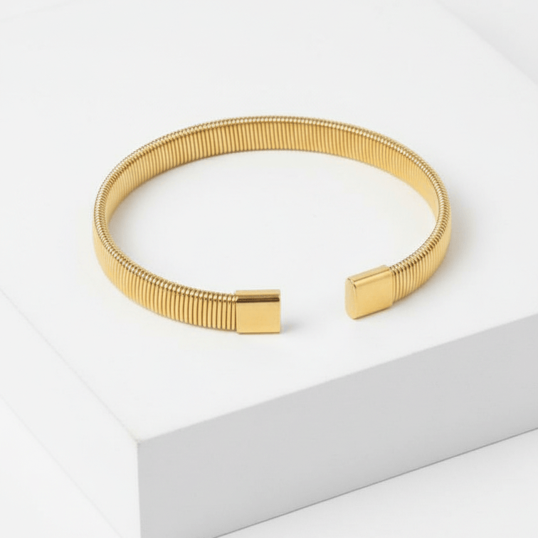 Gold Ribbed Coil Bangle Bracelet on white square pedestal