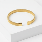Gold Ribbed Coil Bangle Bracelet on white square pedestal