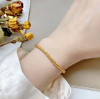 Gold bracelet on a wrist with dried flowers in the background