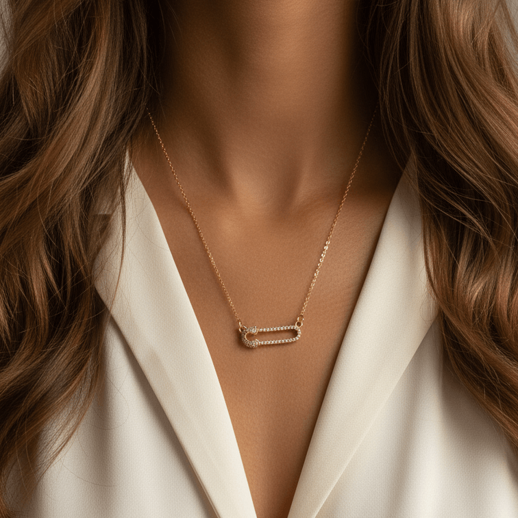 Gold Safety Pin Pendant Necklace with a rectangular pendant worn by a person in a white outfit.