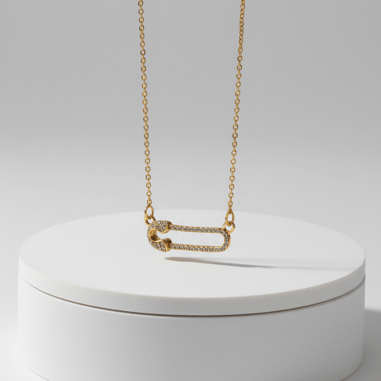 Gold Safety Pin Pendant Necklace on a white round box against a light gray background