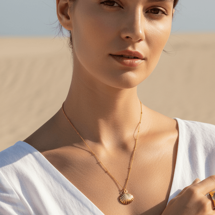 Gold Scallop Shell Pendant Necklace with a desert landscape in the background