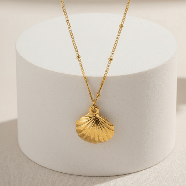 Gold Scallop Shell Pendant Necklace with a shell pendant on a white cylindrical stand