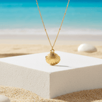 Gold Scallop Shell Pendant Necklace with a shell pendant on a white platform by the beach