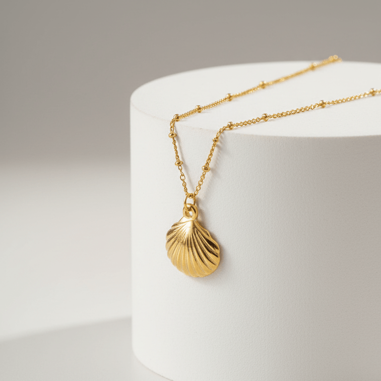 Gold Scallop Shell Pendant Necklace with a shell pendant on a white cylindrical object against a light gray background