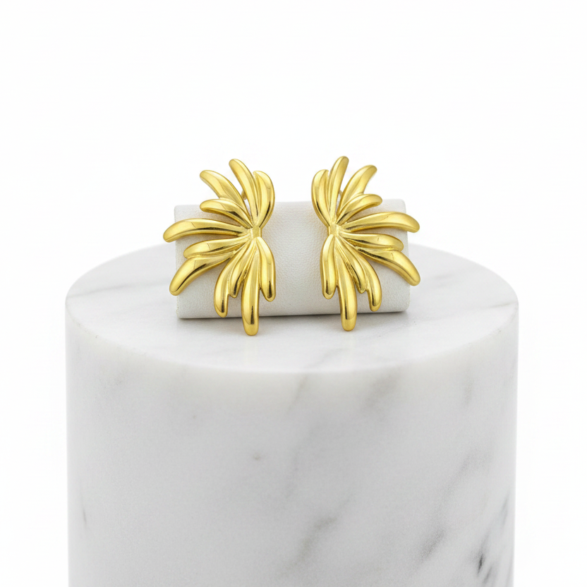 A pair of Gold Sculpted Petal Stud Earrings displayed on a white rectangular block atop a white marble cylinder against a white background.