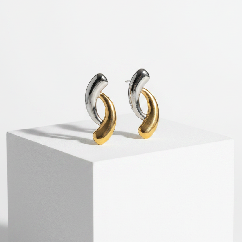 A pair of Gold & Silver Intertwined Stud Earrings, displayed on a white geometric pedestal against a clean white background.