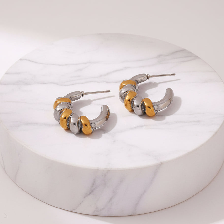 A pair of silver and gold hoop earrings with a textured, segmented design, shown on a light off-white background with dimension and weight labels.